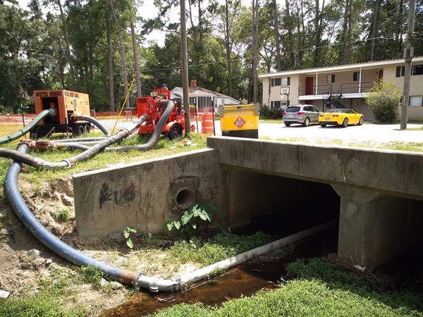 [Pipe under bridge by apartments]