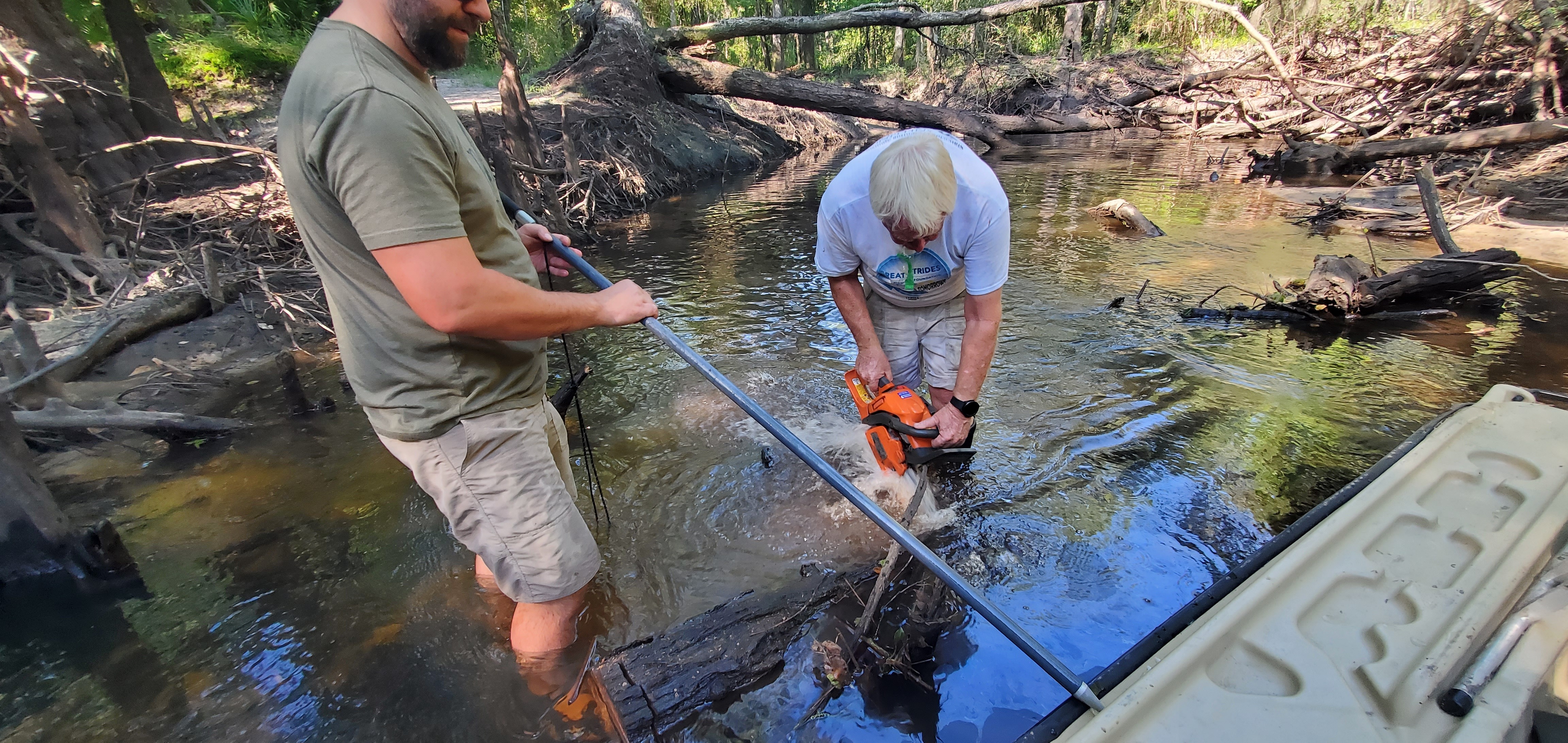 Phil saws a log; Jan fends off the boat