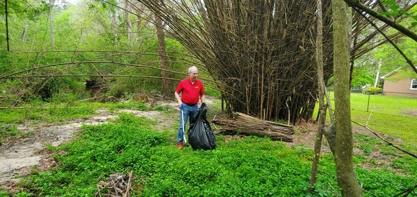 [Mayor picking up trash between two exotic invasive species, 2023:03:25 08:48:20, 30.8636422, -83.3021599]