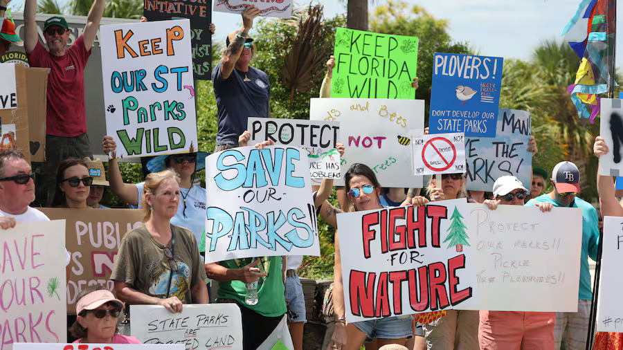 People gather at the entrance to Honeymoon Island State Park on Tuesday to speak and demonstrate against the Great Outdoors Initiative proposal to add golf courses, hotels, pickleball courts and other developments to nine Florida state parks. [ DOUGLAS R. CLIFFORD | Times ]