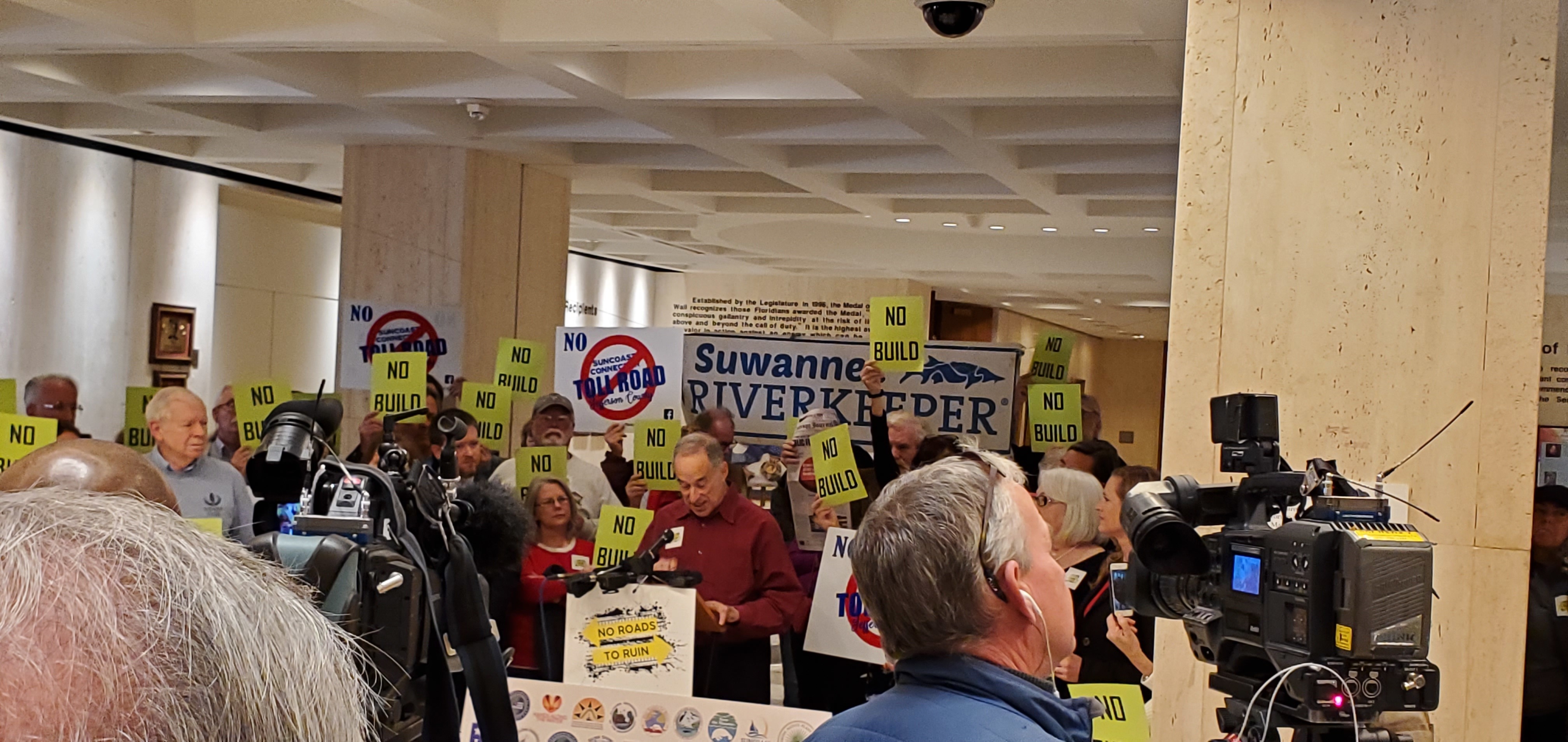 Suwannee Riverkeeper John S. Quarterman beside banner; Mike Roth of OSFR speaking