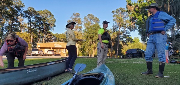 Kim checking a canoe, Shirley signing people in, Holly listening, Chris at the ready