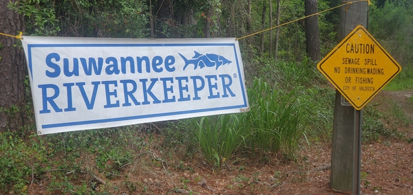 [Suwannee Riverkeeper Banner and Valdosta Sewage Spill sign at Sugar Creek 2023-07-28, 09:52:42]