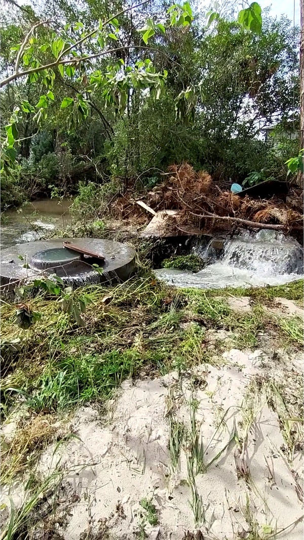 [Sewage spewing from two manholes into One Mile Branch below Wainwright Drive]