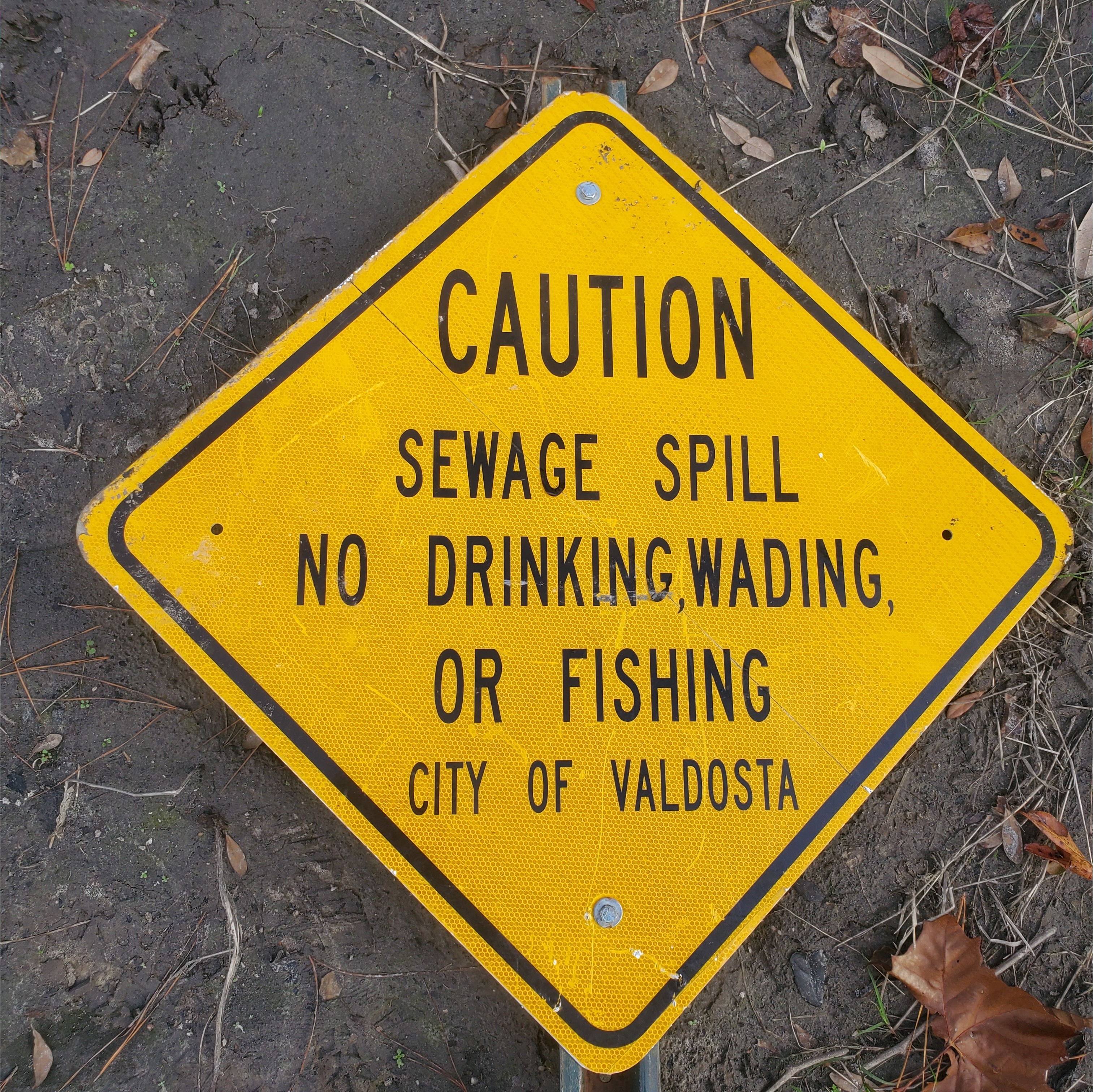 Closeup, sewage spill sign turned face up, 14:41:47, 30.8624580, -83.3186479