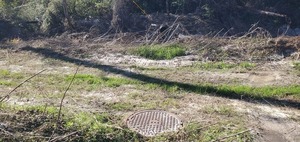 [Closeup, manhole, Westbrook Circle sewer line, Sugar Creek, 2025:01:02 13:10:46, 30.8505952, -83.3143212]