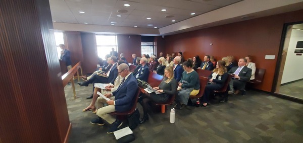 [Audience, Joe Hopkins front left, Drew Jones speaking against the bills]