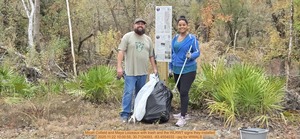 [Micah Cofield and Maya Loizeaux with trash and the WLRWT signs they installed, 2025:11:22 10:00:55, 30.7124093, -83.4554032 --jsq for WWALS]